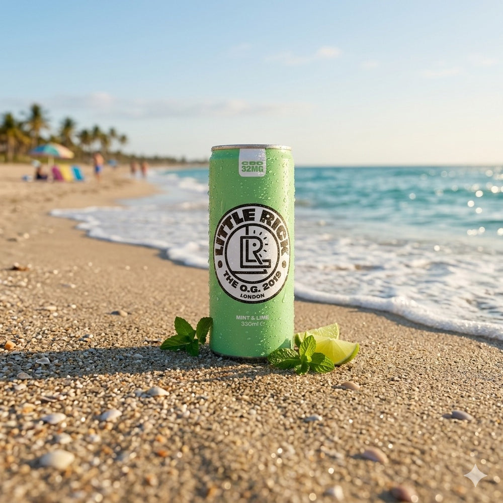A green Little Rick drink can on sandy beach with ocean and blue sky in the background.