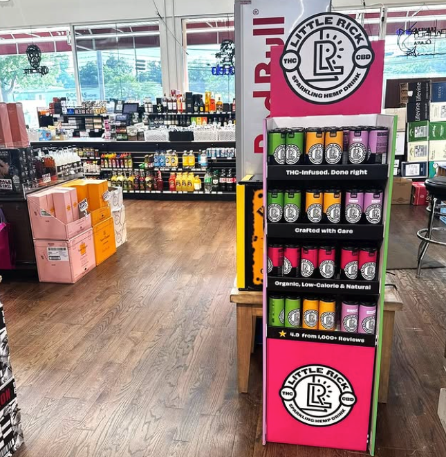 Display of Little Rick CBD products in a store setting with various items in the background.